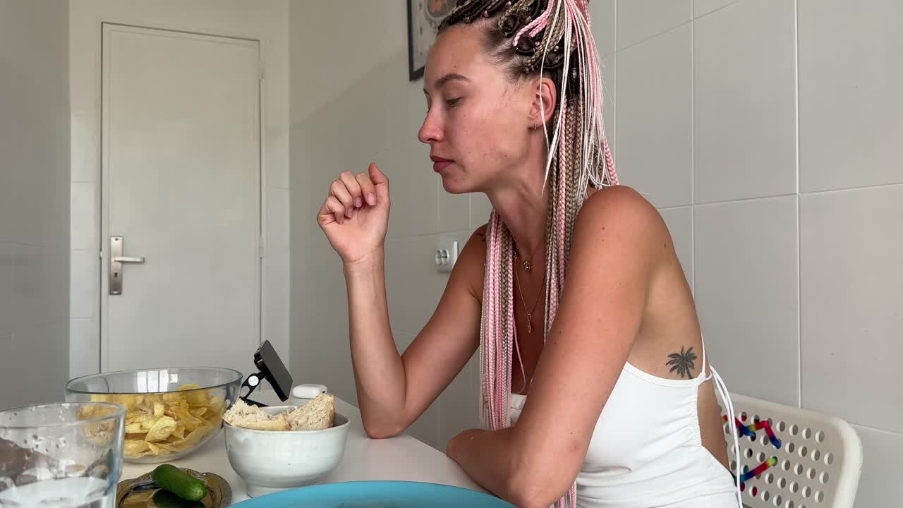 Mujer joven con trenzas comiendo patatas fritas en una mesa