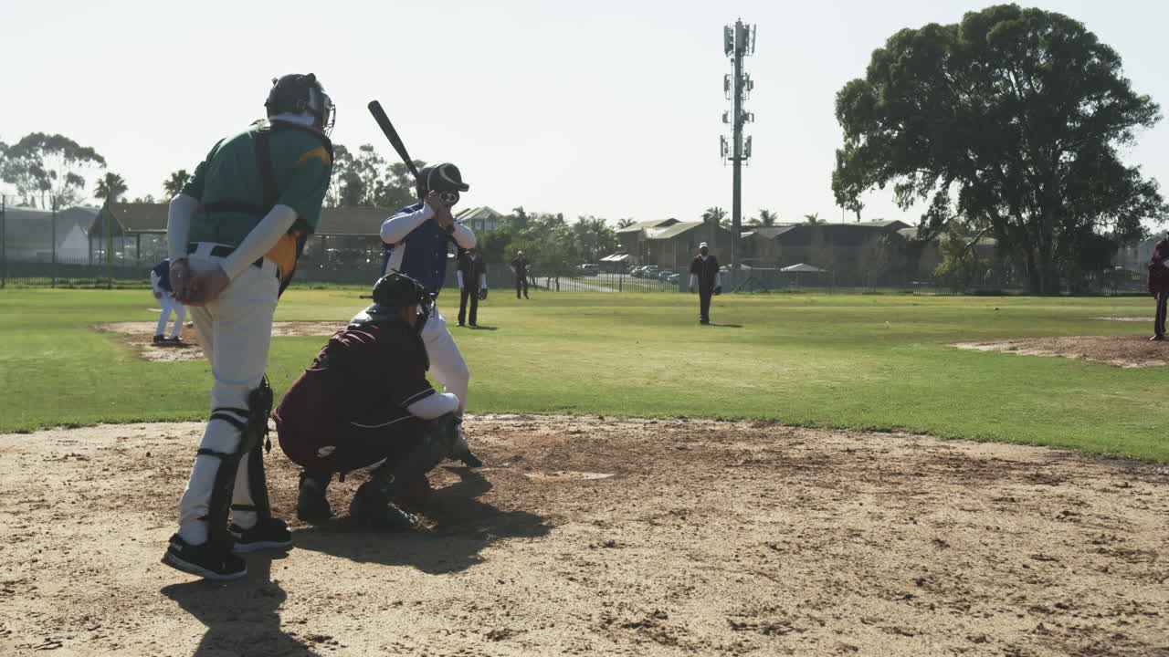 Multiracial male baseball players and male umpire, hitting ball and running on a pitch, slow motion
