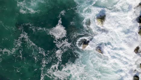 drone hovering over ocean as waves come in