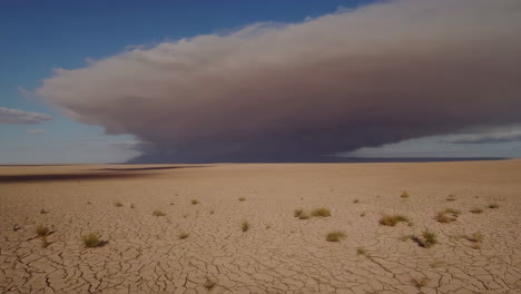 a massive storm over a dry, cracked desert landscape