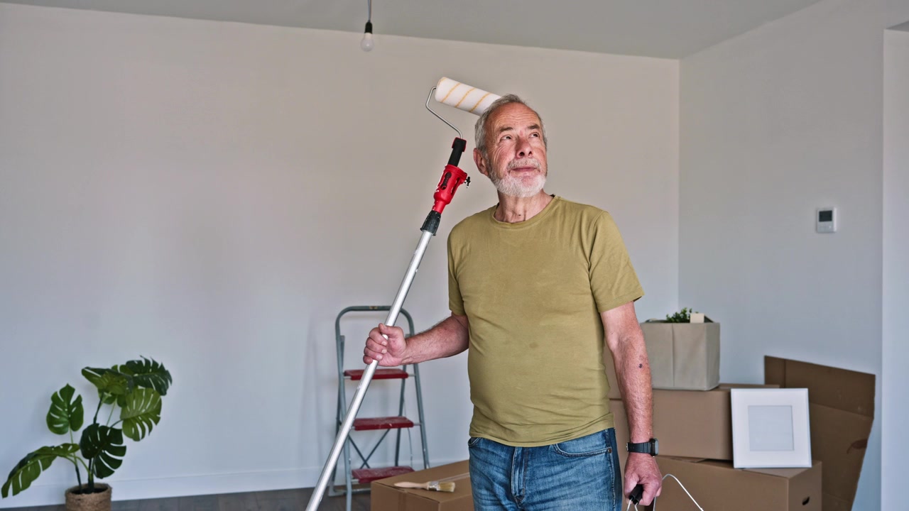 Elderly Man with Paint Roller and Tray in Empty Room