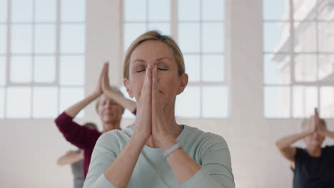 portrait yoga class beautiful mature woman exercising healthy meditation practicing prayer pose enjoying group physical fitness workout in studio