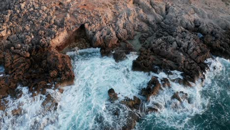 toma de drones de olas rompiendo en la costa durante la puesta de sol y la hora dorada en mallorca