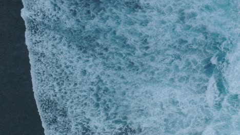 Top-Down-Slow-Motion-Drone-of-wave-action-at-low-tide-over-coral-and-rock-reef-Nyang-Nyang-Beach,-Bali,-Uluwatu-Indonesia