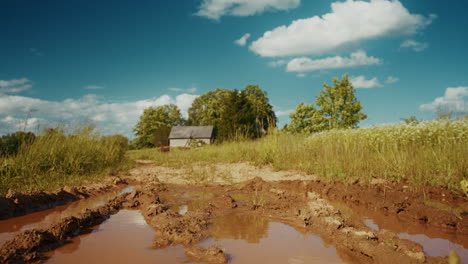 muddy country road with farmhouse in background