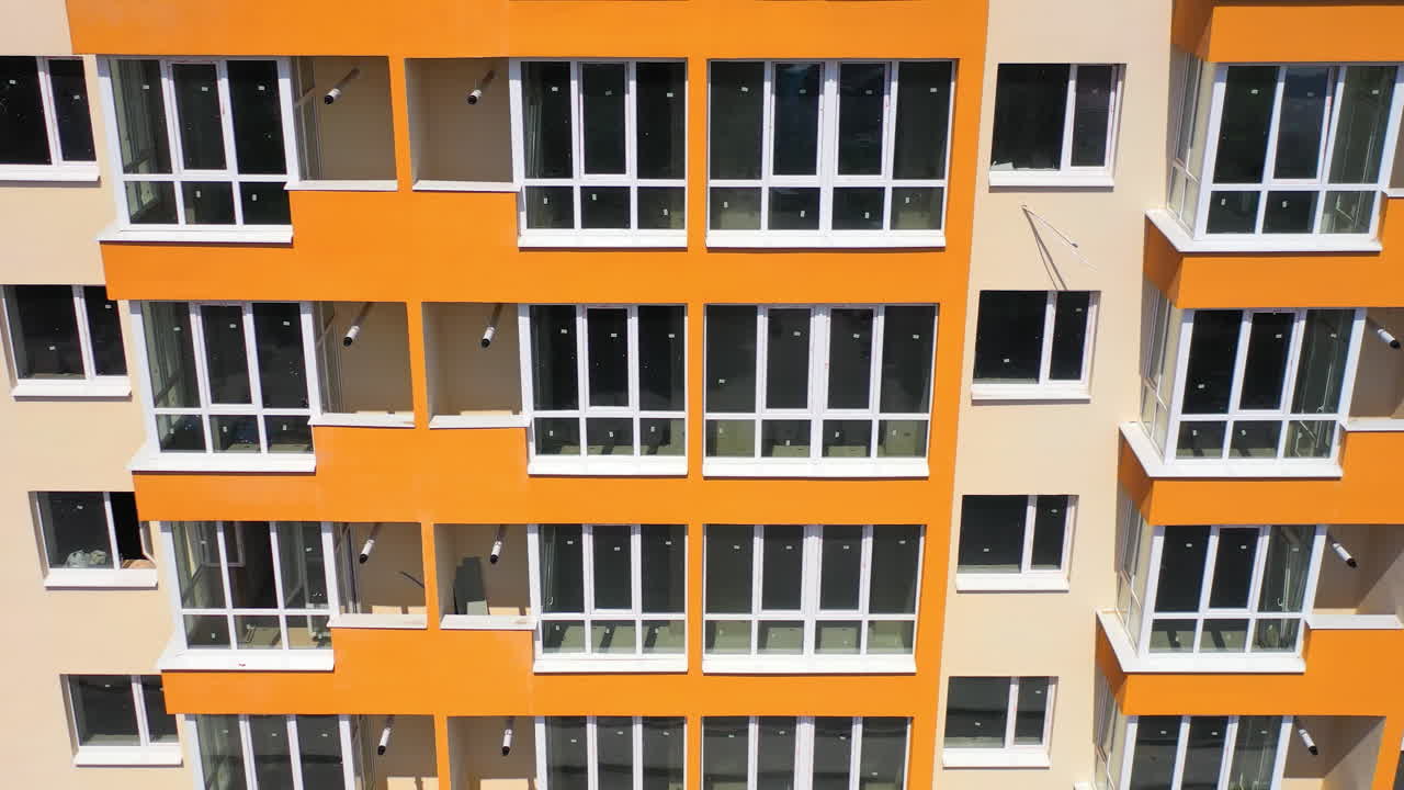 New block of flats with colorful walls. Contemporary high-rise building with large windows. Multi storey house for residents in the city.