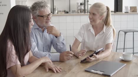 colegas de contenido viendo la pantalla de la tableta y sentados en la mesa