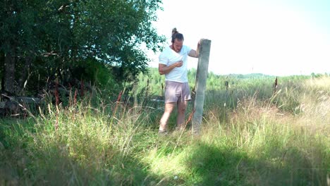 un hombre con barba sosteniendo un poste de hormigón acostado en la hierba