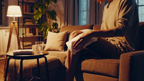 woman applying a compress to her knee on the couch at night