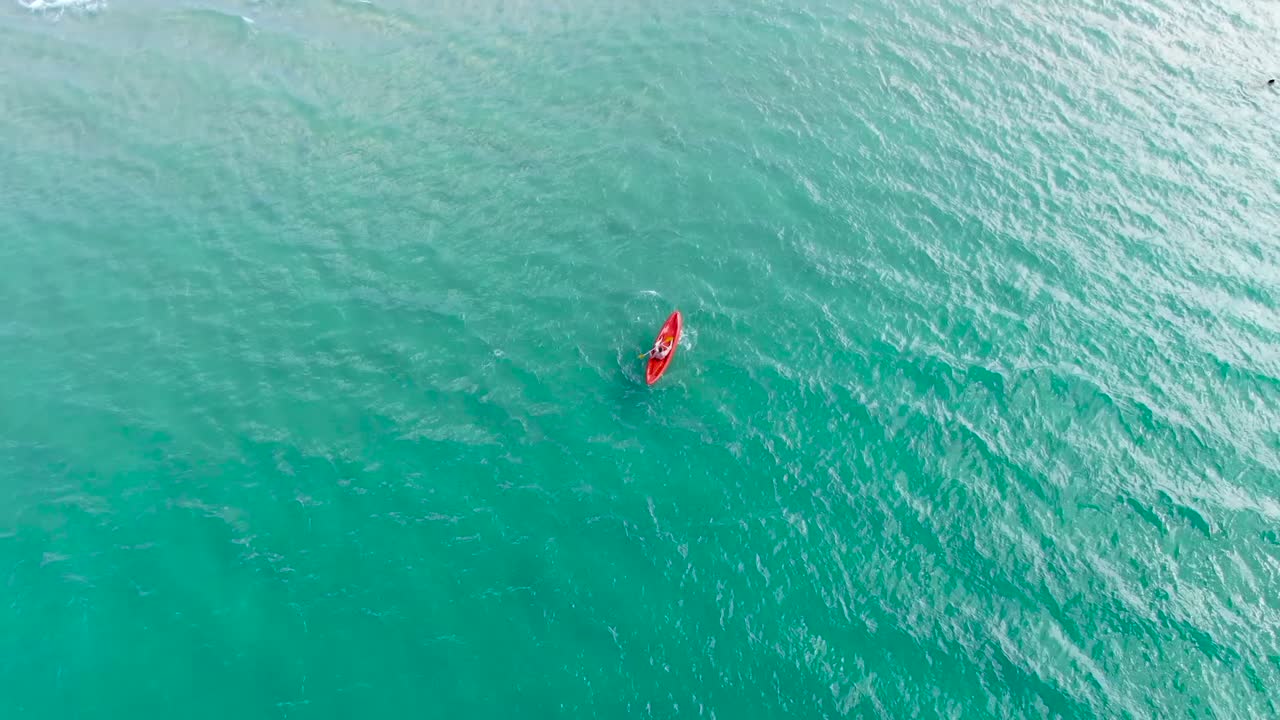 A man doing kayaking in crystal blue water, from above