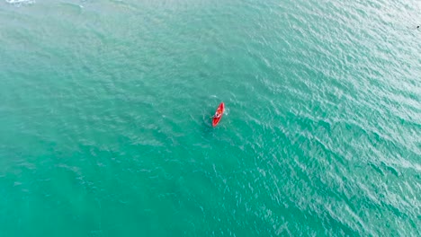 A-man-doing-kayaking-in-crystal-blue-water,-from-above