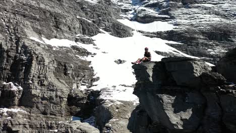 el hombre se sienta solo descansando en la ladera de la montaña con equipo protector de escalada