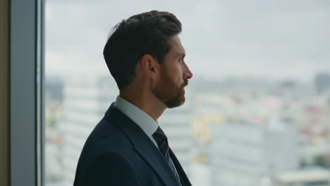 man standing office window watching at city view close up. serious businessman.