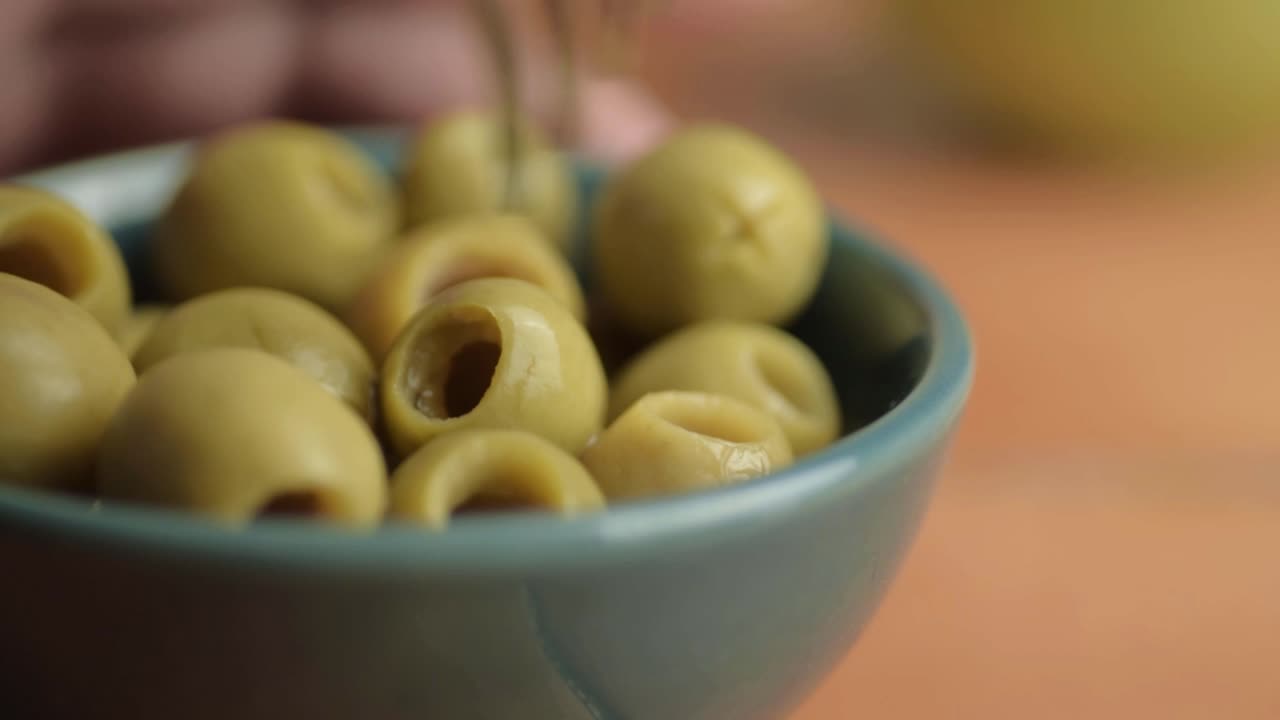 Snacking on green olives with fork macro shot