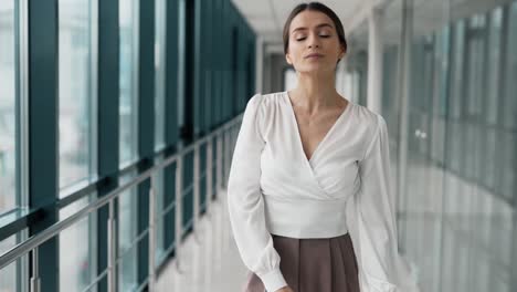 mujer joven de negocios sonriendo y girando en un corredor de vidrio