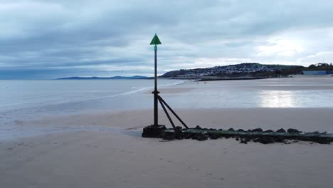 coastal tide marker aerial view low slow right orbit across moody overcast low tide seaside beach