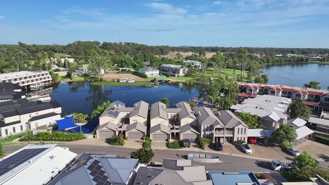 Aerial reveal of a boat on the lagoon and the resort apartments on the shore of Lake Mulwala