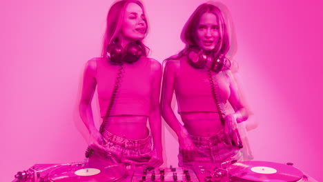 identical twin female djs dancing behind record turntables