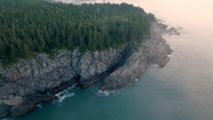 Un drone in orbita cattura l'alba sulla "Bold Coast" del Maine con la nebbia sull'acqua.