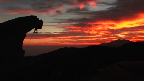 Mittlere-Aufnahme-Eines-Silhouetten-Kletters,-Der-An-Einem-überhängenden-Felsen-Hängt