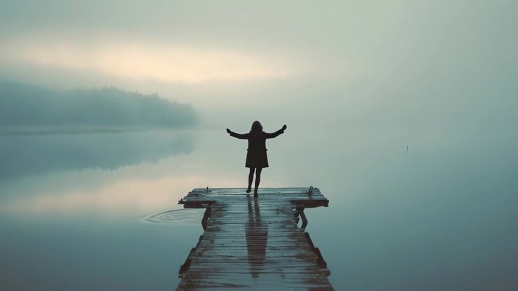 Woman Standing on Wooden Pier Overlooking Foggy Lake