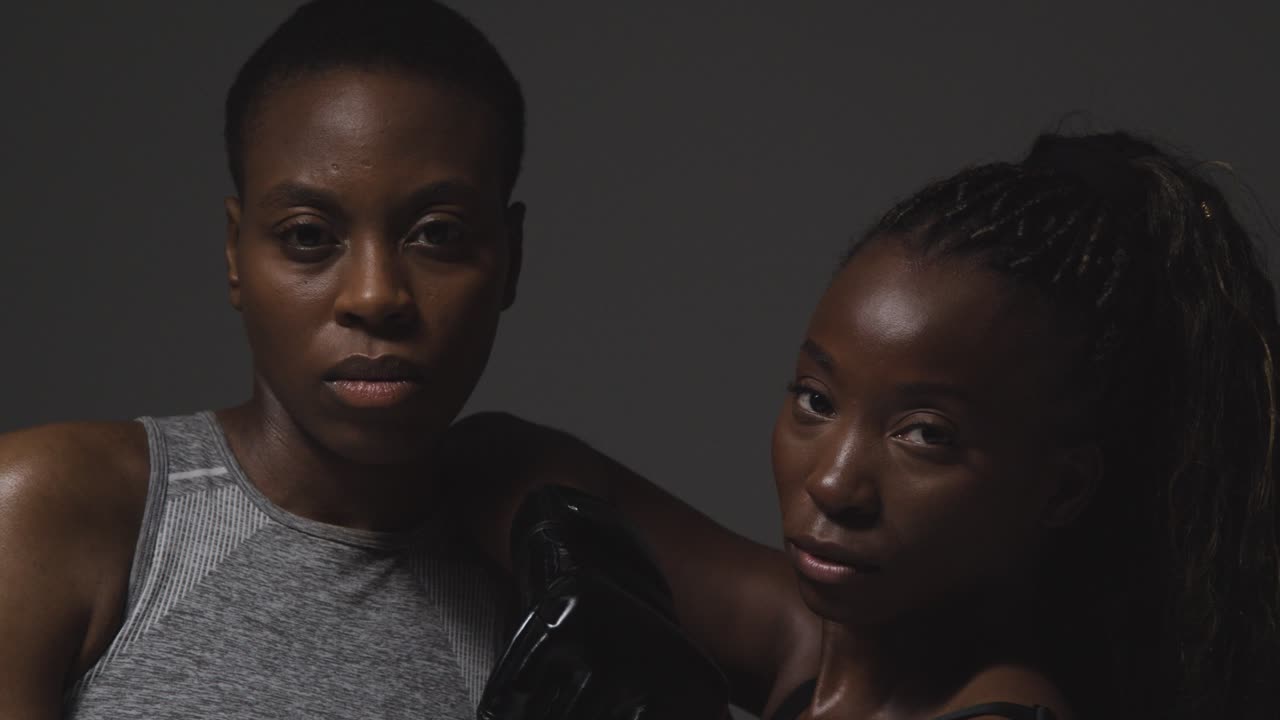 트레이너와 스파링하는 권투 장갑을 입은 여성의 클로즈업 스튜디오 초상화  ⁇