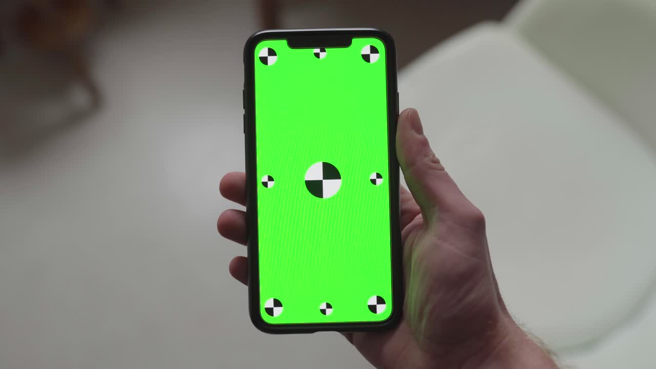 dos manos sosteniendo un teléfono inteligente con pantalla verde y marcadores de seguimiento, cambiando la orientación de retrato a paisaje a retrato a paisaje y de nuevo a retrato