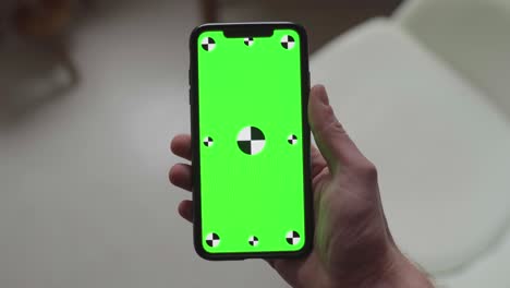 dos manos sosteniendo un teléfono inteligente con pantalla verde y marcadores de seguimiento, cambiando la orientación de retrato a paisaje a retrato a paisaje y de nuevo a retrato