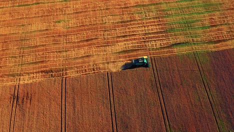 aerial view of harvester cutting crop of wheat on harvesting season