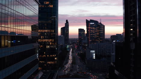 Backwards-reveal-of-downtown-skyscrapers-against-twilight-sky.-Busy-multilane-road-and-intersection.-Warsaw,-Poland