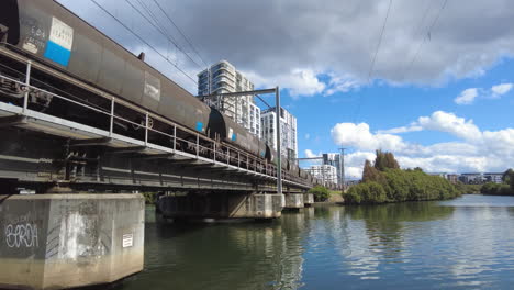 Un-Gran-Tren-De-Carga-Se-Mueve-Lentamente-A-Través-De-Un-Puente-Sobre-El-Agua-En-Sydney,-Australia