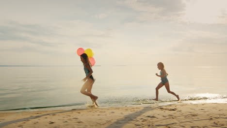 infancia feliz: dos hermanas corriendo una alrededor de la otra en la playa se divierten a cámara lenta