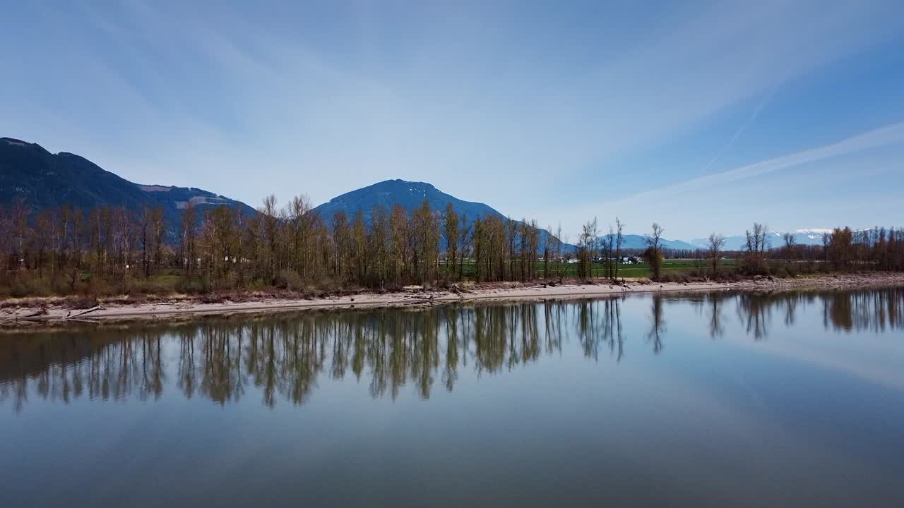 un dron de zoom disparado hacia las montañas en mission, bc, canadá sobre el río fraser en un día nublado azul