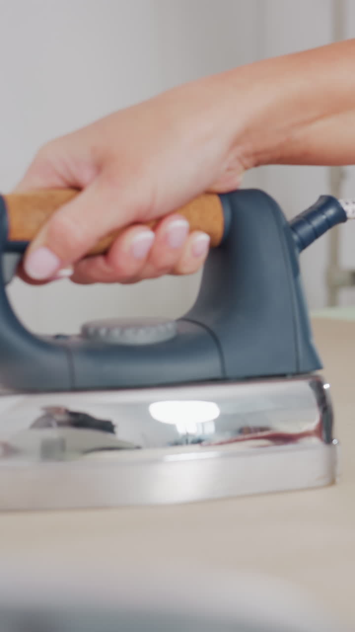 Skilled hands ironing textile seams on worktable, Fabric being carefully pressed by expert hands in sewing room, Artisan smoothing fabric seams with sewing machine backdrop in busy workshop