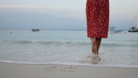 Toma-En-Cámara-Lenta-De-Piernas-Y-Pies-Descalzos-De-Mujer-Caucásica-Vestida-De-Rojo-Caminando-Hacia-El-Mar-En-La-Playa-En-La-Isla-De-Asu,-Norte-De-Sumatra,-Indonesia