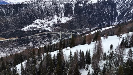 Wide-drone-shot-of-the-ultra-modern-Ganter-Bridge-between-the-high-swiss-alps-covered-with-white-snow