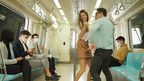 mujeres jóvenes escuchan música en sus teléfonos inteligentes y bailan descuidadamente en su viaje en el metro