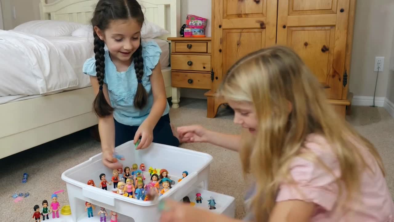 Two Young Girls Playing with Dolls on the Floor in a Bedroom