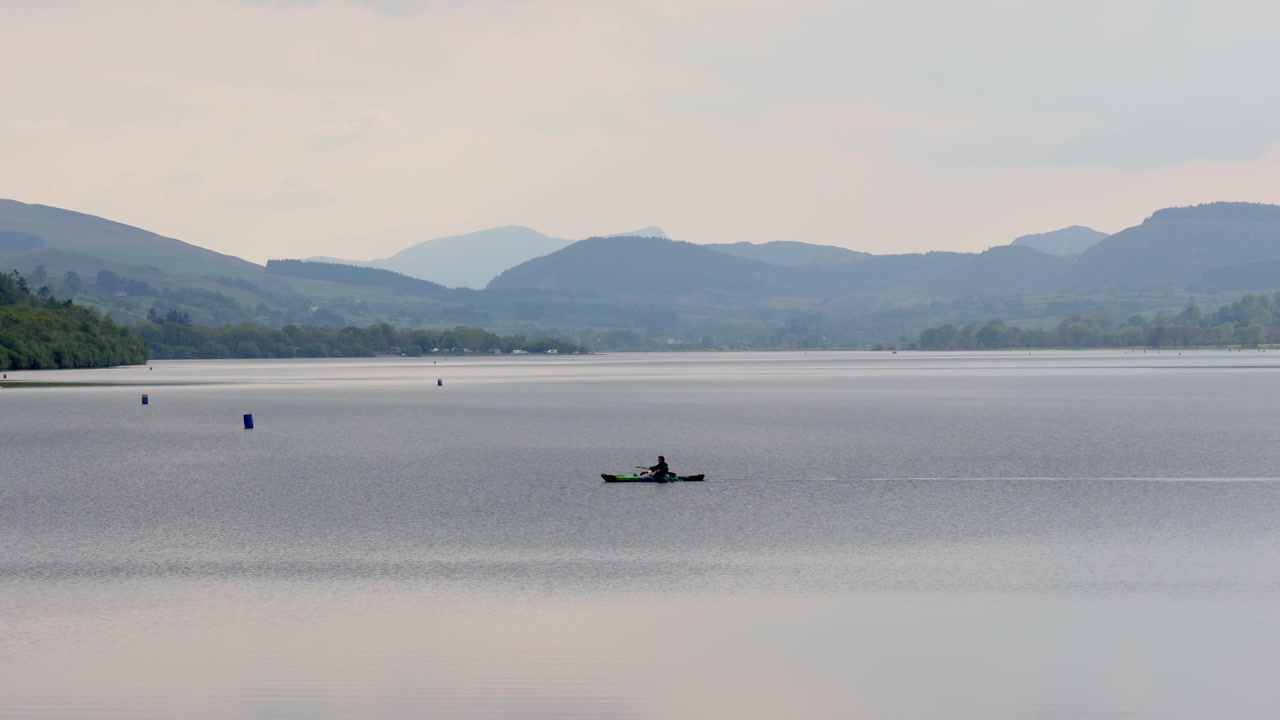 En kano padles over Bala-søen eller Llyn Tegid på en stille forårsaften. Snowdonia Nationalpark. Gwynedd. Wales.