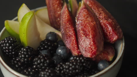 fresh berries and figs bowl outdoors on a dark wooden table