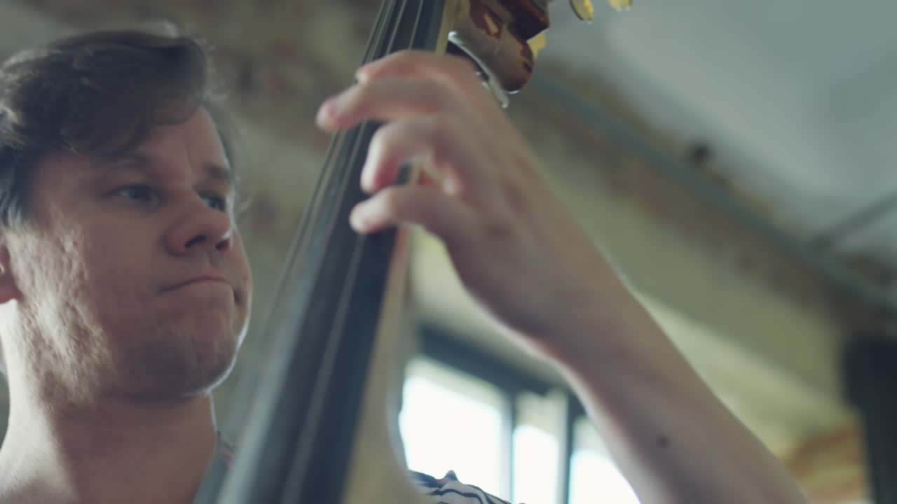 Man playing a double bass with a focused expression