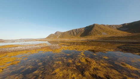 backwards flying fpv drone aerial of the crest of a mountain range, lofoten islands in norway, impressive low flight