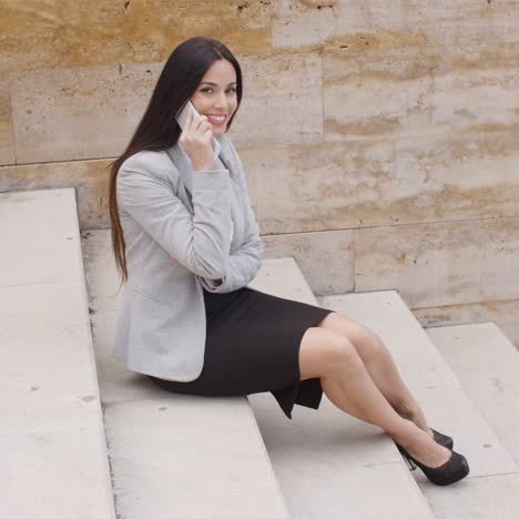 Cute-business-woman-sitting-on-steps-with-phone