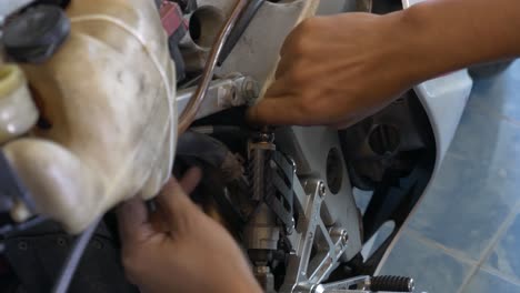 imágenes de primer plano del mecánico que trabaja en la instalación del cable de freno para motocicleta