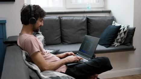 hombre caucásico con auriculares escribiendo en una computadora portátil en casa, comunicación en las redes sociales