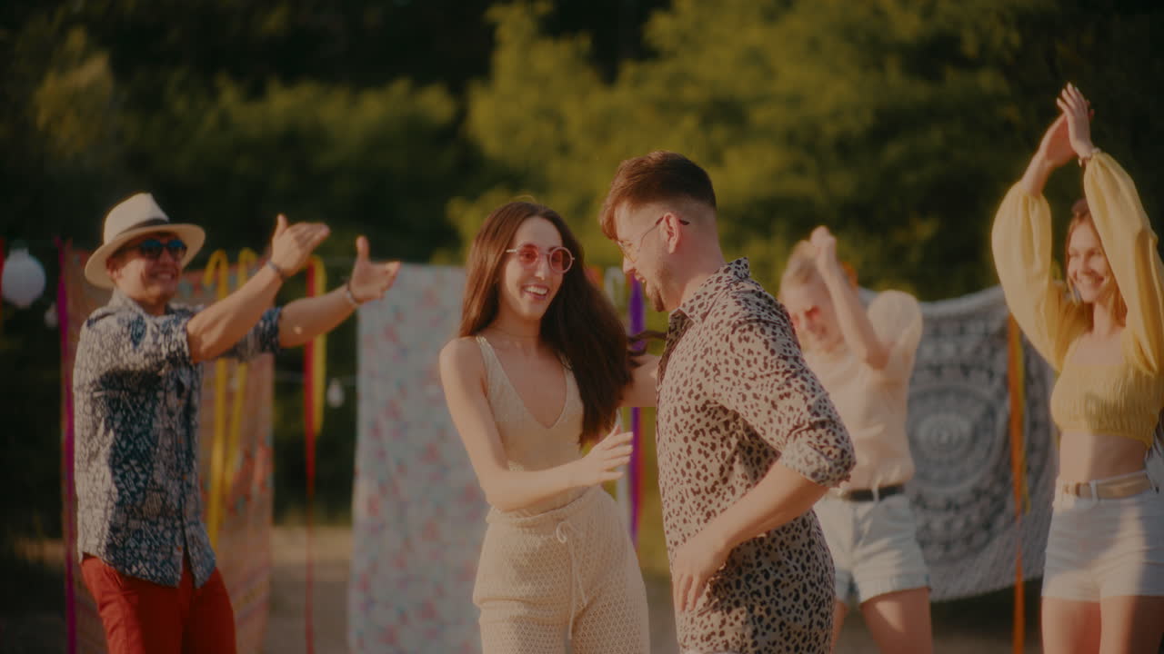 pareja feliz bailando bachata mientras los amigos aplauden en la playa