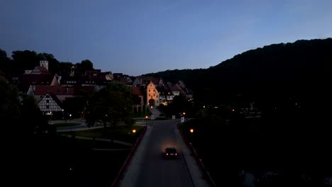 aerial shot of an european old town at dusk with illuminated historic buildings and cars driving by