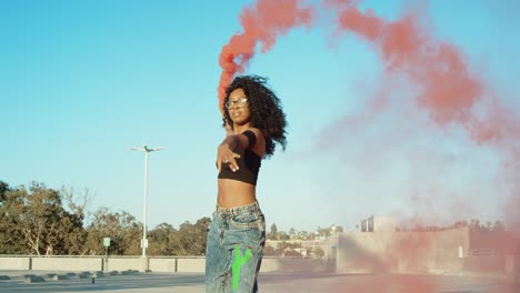 young woman dancing outside with smoke grenade at sunset on rooftop parking garage