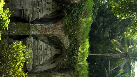 Tiro-Inclinado-Hacia-Arriba-De-Las-Ruinas-Históricas-De-Un-Templo-En-Bali,-Indonesia,-Con-Una-Fuente-Y-Vista-De-La-Densa-Jungla