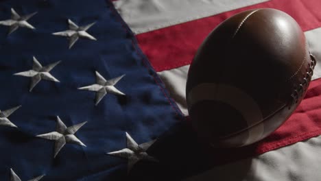 low key lighting studio shot of american football on stars and stripes flag 8